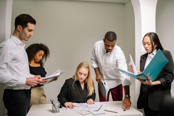 Diverse team working together in an office setting, reviewing documents and collaborating on projects.
